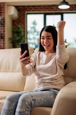 Otantik görünümlü Asyalı kadın telefon kazanma ve mutlu duygularla mobil online video oyunları oynuyor. İnternet video oyunları uygulama oyunu film sosyal internet iletişimi izliyor