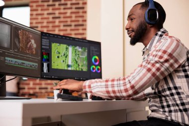 Professional creator using software to edit video footage on multiple monitors at home, editing movie with production application on computer. Working on film montage to create media content.