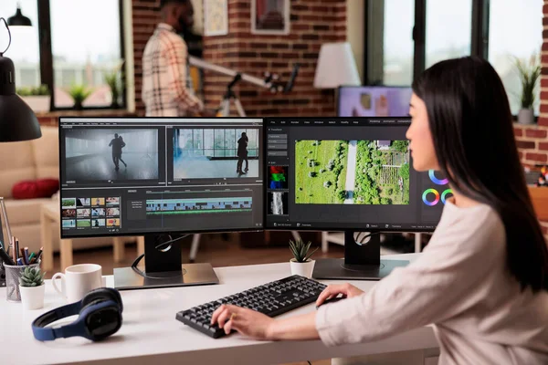 Asian freelancer editing audio film montage with post production software on computer. Videographer working on movie footage edit with color grading and visual or sound effects at home.