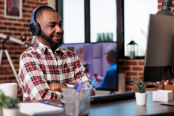 Male Freelancer Using Headphones Working Remotely Computer Home Desk Listening — Stok fotoğraf