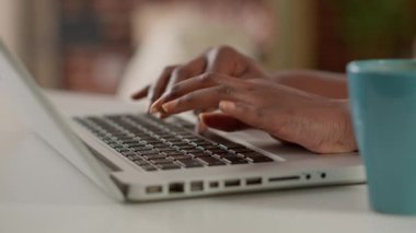 Young adult typing business research information on laptop, browsing internet to work remotely at home. Startup employee using computer and working remote. Handheld shot. Close up.