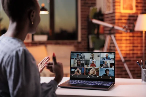 Female african american businesswoman attending business meeting with colleagues using laptop, back view. Company remote team discussing business on teleconference, telecommunications and telework