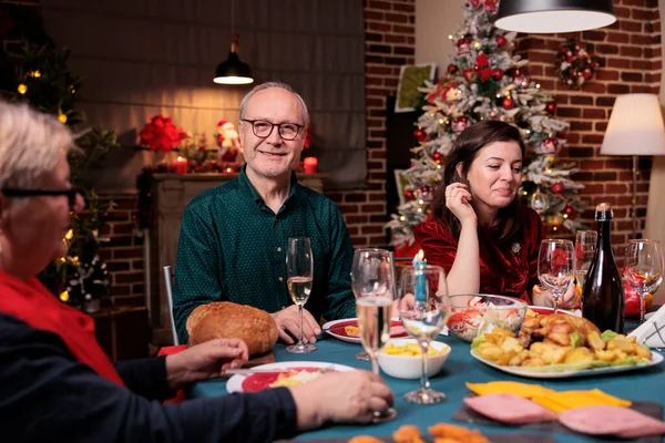 Woman celebrating christmas with family, sitting at festive dinner table with dad at home party. Father and daughter eating home cooked xmas dishes in decorated beautiful place portrait