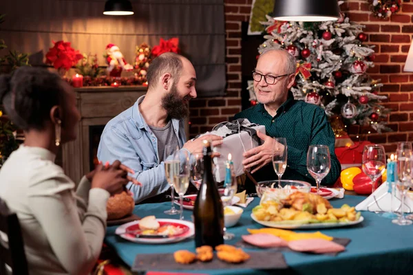 Happy Family Exchanging Christmas Presents Having Dinner Festive Table Celebrating — Stock Fotó