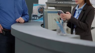 Old man paying checkup visit with credit card at hospital reception desk, making payment and transaction after healthcare appointment. Receptionist helping senior patient to pay for consultation.
