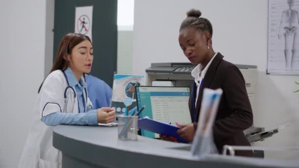 Diverse Team Doctor Receptionist Working Reception Desk Fill Medical Report — стоковое видео