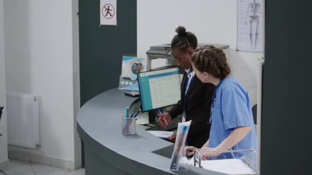 Diverse Medical Team Working Hospital Registration Counter Lobby Helping Senior — Stock video