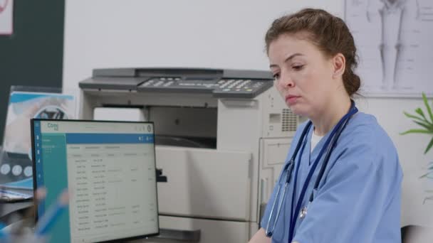 Nurse Using Computer Appointments Reception Desk Facility Lobby Working Report — Wideo stockowe