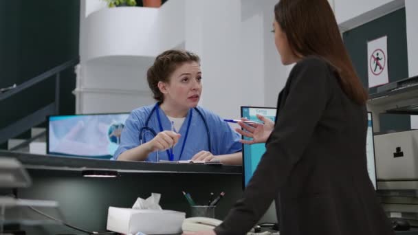 Portrait Medical Assistant Talking Receptionist Hospital Registration Counter Using Appointment — Vídeos de Stock