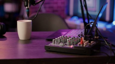 Laptop klavyesine ve ev stüdyodaki podcast masasındaki ses mikserine odaklan. İnternet üzerinden canlı yayın için kullanılan profesyonel ses donanımının ayrıntıları.