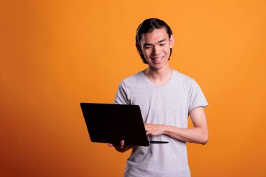 Dizüstü bilgisayarda çalışan serbest çalışan genç bir öğrenci, online eğitim dersleri izleyen bir öğrenci. Gülümseyen Asyalı uzaktan çalışan taşınabilir bilgisayar kullanıyor, serbest meslek kavramı