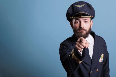 Kamerayı işaret eden ciddi bir uçak pilotu, havacılık akademisi işe alımı, üniforma giyen bir yüzbaşı ve şapka önü portresi. Ceketinde kanat rozeti olan orta yaşlı bir havacı.