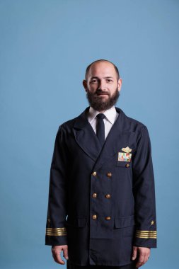 Gülümseyen uçak kaptanı orta boy üniforma giyiyor, yakın plan fotoğrafı çekiyor, uçak pilotu kameraya bakıyor. Profesyonel takım elbiseli orta yaşlı pilot, uçuş ekibi üyesi.