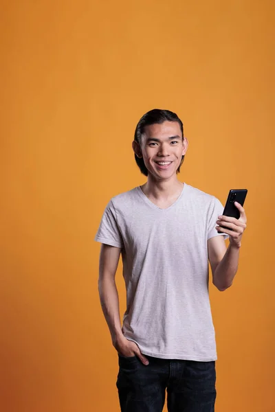 Młody Uśmiechnięty Azjata Korzystający Smartfona Wysyłający Wiadomości Mediach Społecznościowych Radosny — Zdjęcie stockowe