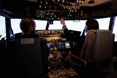 Pilot pilot kabinindeki torpido gözündeki düğmeleri kullanarak kaptana kalkış ve uçuş için yardım eden kadın pilot. Uçaklar seyrüsefer ön camı ve kontrol paneli olan uçak jeti uçuruyor..