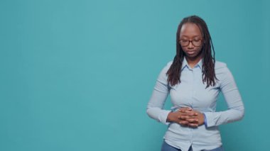 African american relaxed woman posing in front of studio camera, standing with hands crossed. Serious casual person with deep focused look feeling confident and successful over background.