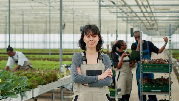 Portrait Confident Woman Posing Arms Crossed Greenhouse While Farm Workers — Stock Photo, Image