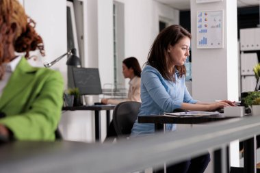 Ortak çalışma alanındaki masa başında çalışan yoğun bir şirket çalışanı, iş yerindeki şirket müdürü, yan görüş. Modern ofiste dizüstü bilgisayarda yazan çekici, ciddi bir kadın, seçici bir odaklanma.