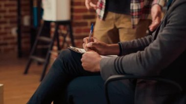 Afrikalı Amerikalı uzman erkeklerle terapi seansında notlar alıyor, evlilik çatışmalarını dinliyor ve profesyonel tavsiyeler veriyor. Danışmanlık yapmak için kağıtlara rapor yazıyorum. Kapat..