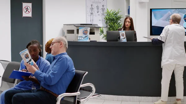 Female Receptionist Talking Senior Doctor Reception Counter Medical Facility Waiting —  Fotos de Stock