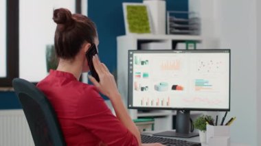 İş danışmanı telefon almak için akıllı telefonu kullanıyor, araştırma stratejisi ve veri şeması geliştirme hakkında sohbet ediyor. Ofis çalışanı başlangıç masasında cep telefonuyla konuşuyor..