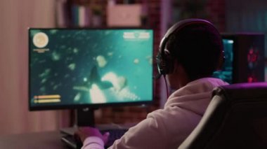 Over shoulder view of gamer feeling unhappy after losing difficult level in online space shooter on gaming pc at home. Man playing internet multiplayer game disappointed after failing competition.