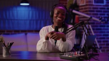 Afrikalı Amerikalı kadın vlogger izleyicilerle konuşurken ses karıştırıcı ve mikrofon kullanarak podcast yapıyor. Podcast stüdyosundan çevrimiçi sosyal medya sayfası için içerik oluşturan ünlü etkileyici.