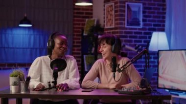 İki kadın, profesyonel mikrofon ve ses karıştırıcı kullanarak günlük konuşmaları kaydediyor. Çevrimiçi podcast sunucusu Afro-Amerikan etkileyicisiyle dijital içerik oluşturarak konuşuyor.