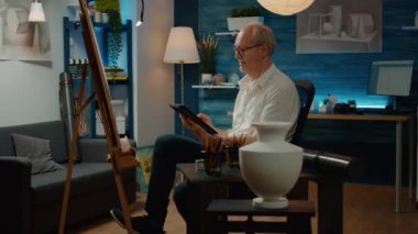 Yaratıcılık ve sanatsal araçlarla ilham aramak için dijital tablet kullanan emekli bir yetişkin. Beyaz tuval üzerinde otantik sanat eskizi oluşturuluyor, modern sanat şaheserleri çiziliyor.