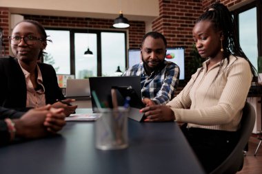Afrika kökenli Amerikalı meslektaşlar, veri araştırmaları ve bilgilerle çevrimiçi sunum yapmak için dizüstü bilgisayar ve tablet kullanarak ofiste fikir alışverişinde bulunuyorlar. E- posta raporu göndermek için belgeler analiz ediliyor.