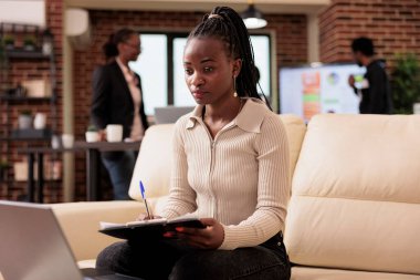 Şirket çalışanı belgelerle ilgili notlar alıyor ve başlangıç ofisinde dizüstü bilgisayar kullanıyor, veri ve analiz raporları üzerinde çalışıyor. Proje yöneticisine evrak işi yapmak ve profesyonel e-posta göndermek.