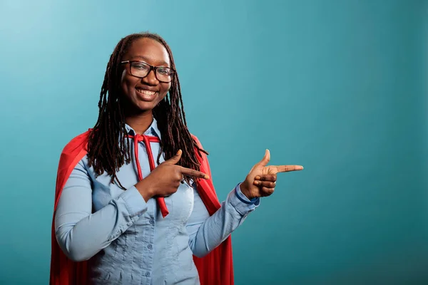 Портрет Молодої Афроамериканки Супергероїні Яка Кидає Пальці Праворуч Посміхаючись Камеру — стокове фото