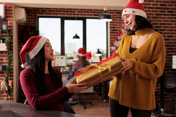 不同的女人在办公室庆祝圣诞节前夕交换礼物盒 在装饰着圣诞树 灯和装饰品的空间里 节日送礼的人 — 图库照片