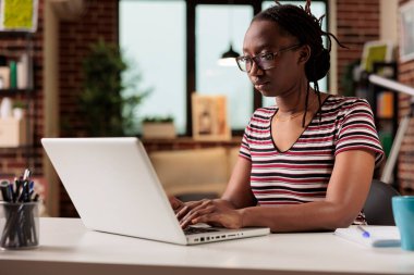 Serbest çalışan, dizüstü bilgisayarlı klavyede yazan ev ofisteki internet bilgilerini arayan biri. Çalışan bilgisayarda mesaj yazıyor, metin yazıyor, çalışma masasında oturuyor.