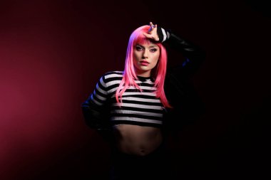 Kendine güvenen, pembe saçlı, kameraya bakan, doğal duygularını ifade eden ve punk tarzı rock 'çı bir güzellik mankeni. Motosikletli deri ceket giyiyordu. Garip bir saç stili vardı. Modern ve şık hissediyordu..