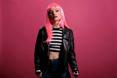 Stüdyoda şık bir deri ceket giyen, punk rockçı tarzıyla kaygısız ve şehvetli hisseden kadın modelin portresi. Pembe saçlara sahip olmak ve funky olmak, arka planda büyüleyici bir moda.