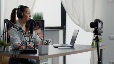 Yaratıcı içerik yaratıcısı ses karıştırıcının düğmelerini ayarlarken video bloğunu ev stüdyosunda kaydediyor. Profesyonel ses donanımı kullanırken izleyicilerle konuşan internet canlı yayın programı sunucusu.