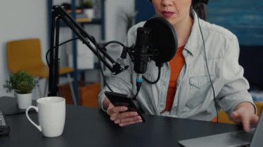 Famous online live radio talk show using smartphone to answer audience messages. Popular social media influencer talking with public on live chat on mobile cell phone. Studio shoot