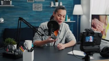 Popular tech enthusiast doing review video of modern wireless mouse while presenting specifications. Digital content creator recording clip of electronic device in living room studio.