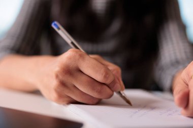 Ofis çalışanı not defterine bilgi yazıyor. Evdeki iş raporları hakkında notlar alıyor. Başlangıç evrakları üzerinde çalışmak ve bilgisayardaki internet dersine katılmak. Kapat..