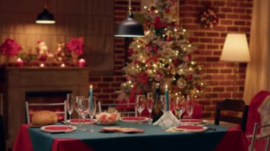 Geleneksel ve otantik kış tatilini kutlamak için konforlu bir ortam. Dekore edilmiş oturma odasında Noel çelenkleri ve yemek takımlarıyla dolu geleneksel Noel yemeği masası..