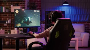 Oyun oynayan kızın kulaklıkla konuşurken internet üzerinden hızlı tempolu uzay nişancısı simülasyon oyunu oynaması. Profesyonel bilgisayar kurulumunda rpg aksiyon oyunu oynayan kadın.