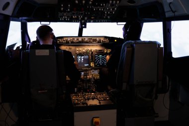 Uçak kokpitinde uçak uçurmak için kontrol komutunu kullanan çeşitli hava ekibi torpido gözünde güç düğmelerine basıyor. Kaptan ve pilot, motor manivelası ile uçak uçuruyor..