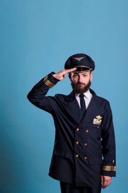 Kendine güvenen bir uçak pilotu, üniforma giyiyor ve şapka takıyor. Ön manzara resmi, kameraya bakan bir uçak kaptanı. Uçak kanatlı sivil kaptan ceketinde rozet, profesyonel uçak mürettebatı üyesi.