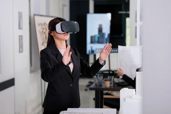 Architect in ar helmet touching virtual building, working on project with augmented reality. Employee engineering looking at 3d model in vr headset, real estate agency developer.