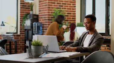 African american man analyzing business data research on laptop, working on professional report to send email. Office worker brainstorming ideas to plan presentation project with charts.