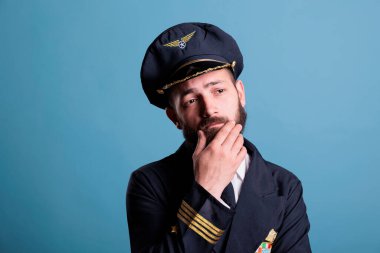 Üniformalı sorgulayan, karar veren, düşünen, karar veren düşünceli bir havayolu kaptanı. Şüpheli yüz ifadesi portresi olan düşünceli bir uçak pilotu.