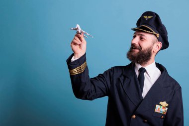Üniformalı gülümseyen pilot uçak modelini tutuyor, havacılık akademisi pilotu uçakla oynuyor. Uçak mürettebatı ticari jet oyuncaklarına bakıyor.