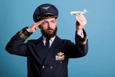 Küçük uçak modelini selamlayan ciddi bir pilot ticari yolcu jet oyuncağıyla oynayan bir uçak pilotu. Ceketinde kanat rozeti olan ciddi bir uçak mürettebatı üyesi.