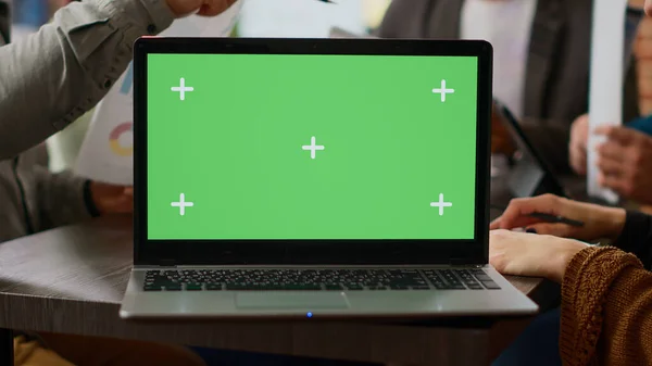 Modern laptop with greenscreen template on display in business office, boardroom meeting. Working with isolated chroma key background and blank mockup copyspace on software. Close up.